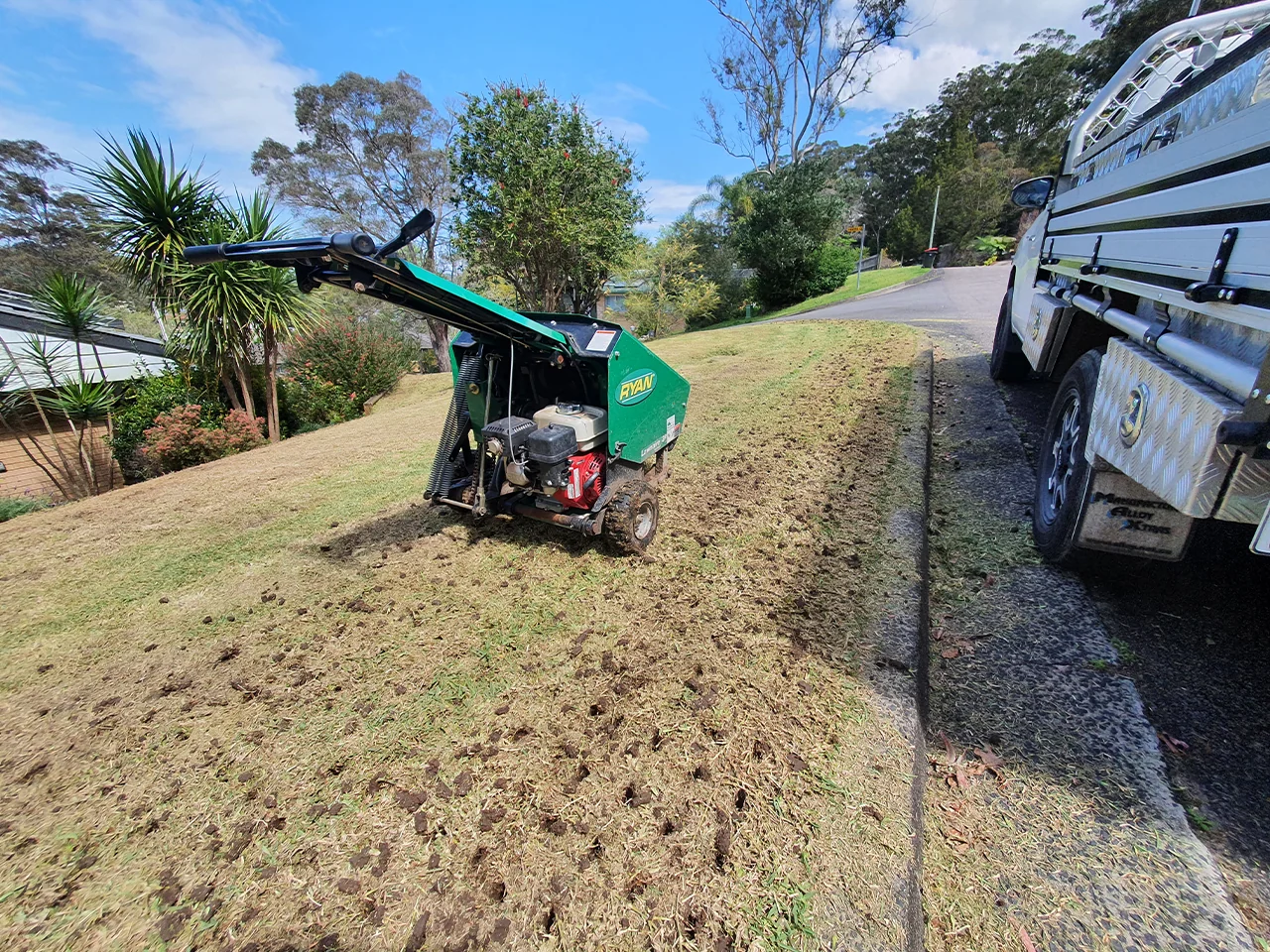 A core aerator being run across a lawn